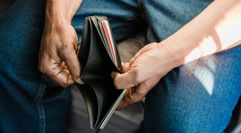 Close-up of a man holding an empty wallet, symbolizing financial crisis and hardship.