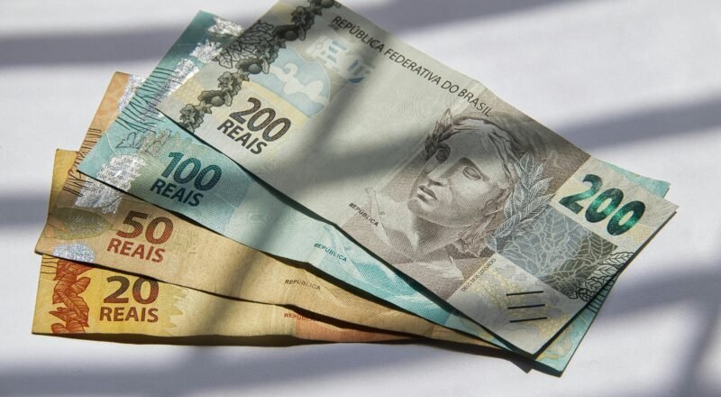 Various Brazilian real banknotes in sunlight, showcasing currency variety.